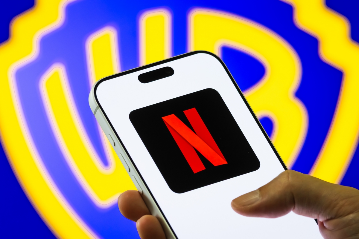 Netflix Logo Displayed on Smartphone Against Warner Bros. Discovery Background